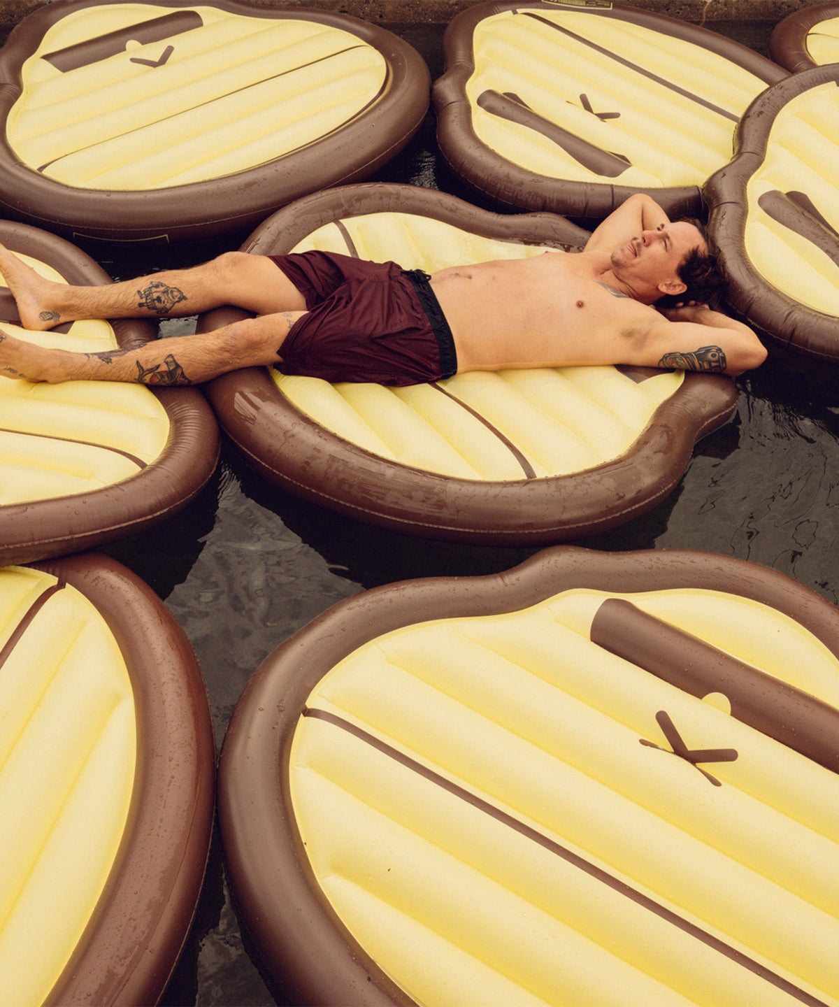 Man relaxing on multiple Sonny Pool Float water mattresses in a pool Sun Bum