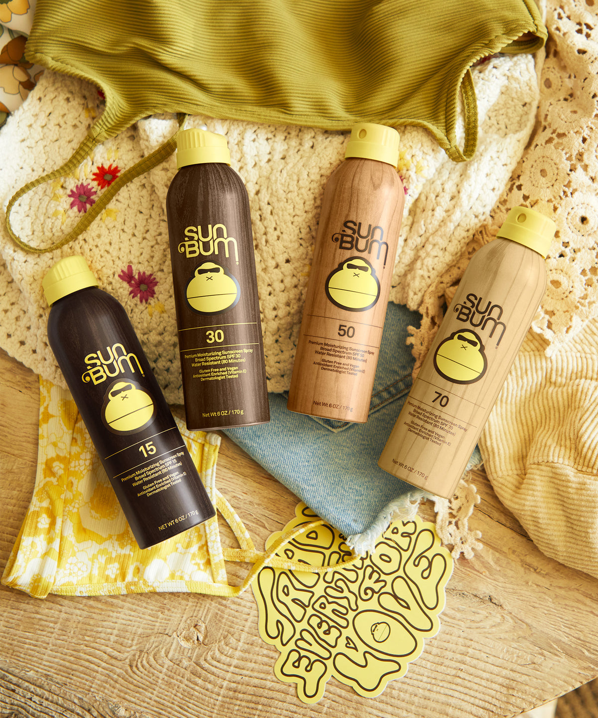 Sun Bum sunscreen bottles with various SPF levels on a textured surface.