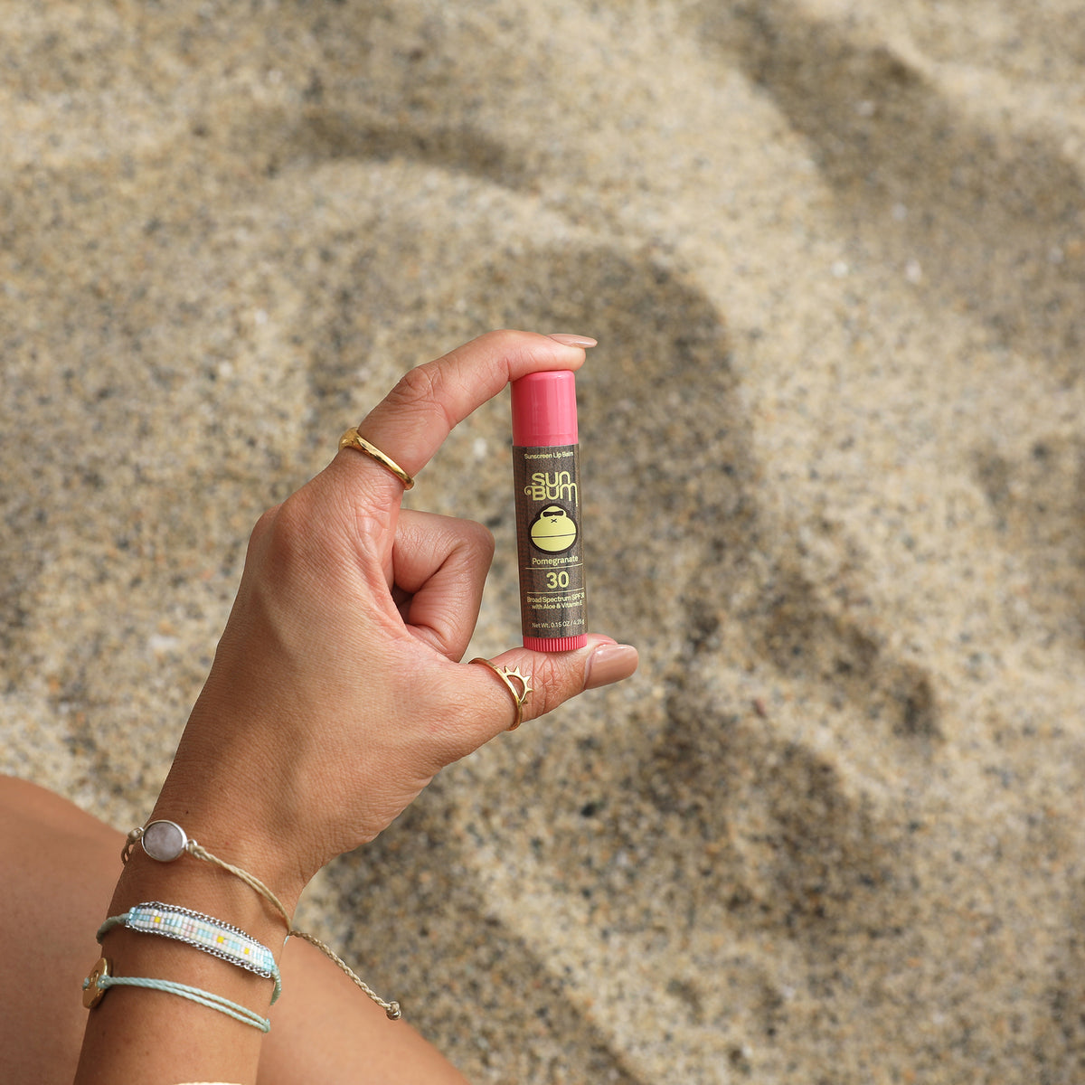 Someone holding a Sun Bum Lip Balm on the beach