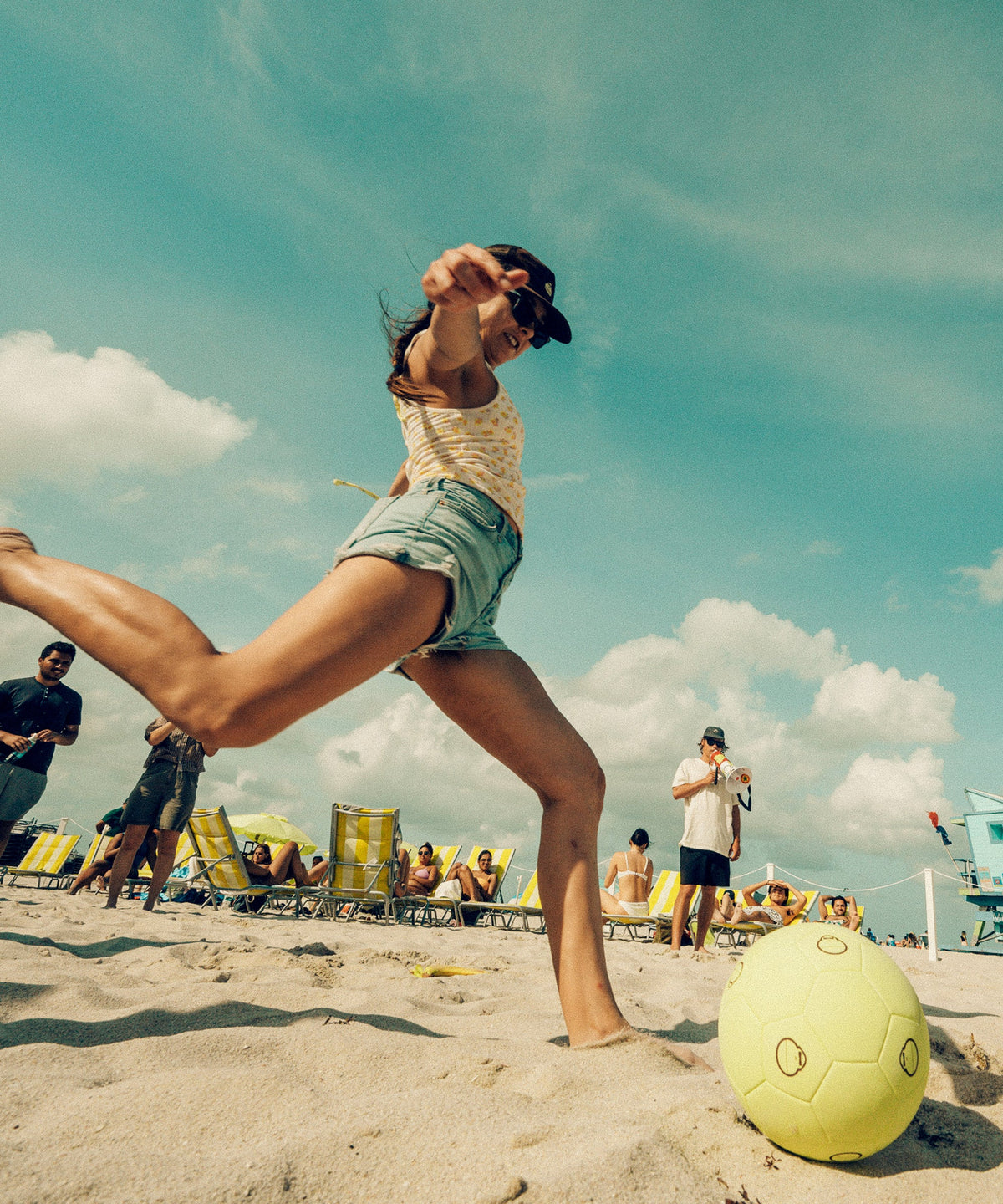 Woman kicks a yellow Sun Bum soccer ball on the beach during a sunny day game - Sonny Gear Collection - Sun Bum